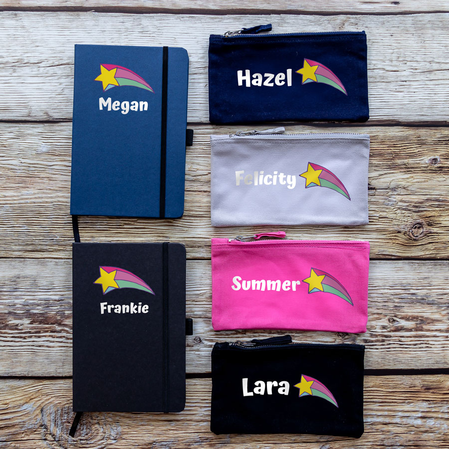 Colour options for back to school bundle. A blue notebook, black notebook, a navy pencil case, grey pencil case, pink pencil case and black pencil case. Featuring name sin white with a pink yellow and blue shooting star.
