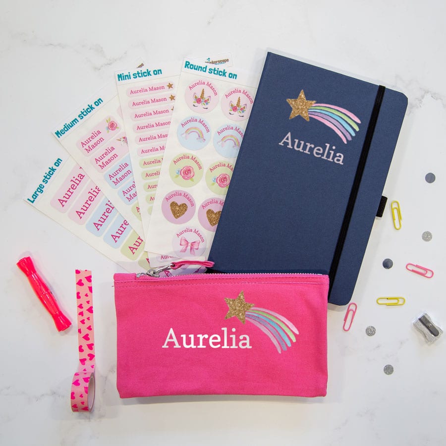 Mega shooting star back to school bundle. Featuring four sheets of stick on name labels, a pink pencil case and a blue notebook with the name Amelia in white with a pastel coloured shooting star with a gold glitter effect.