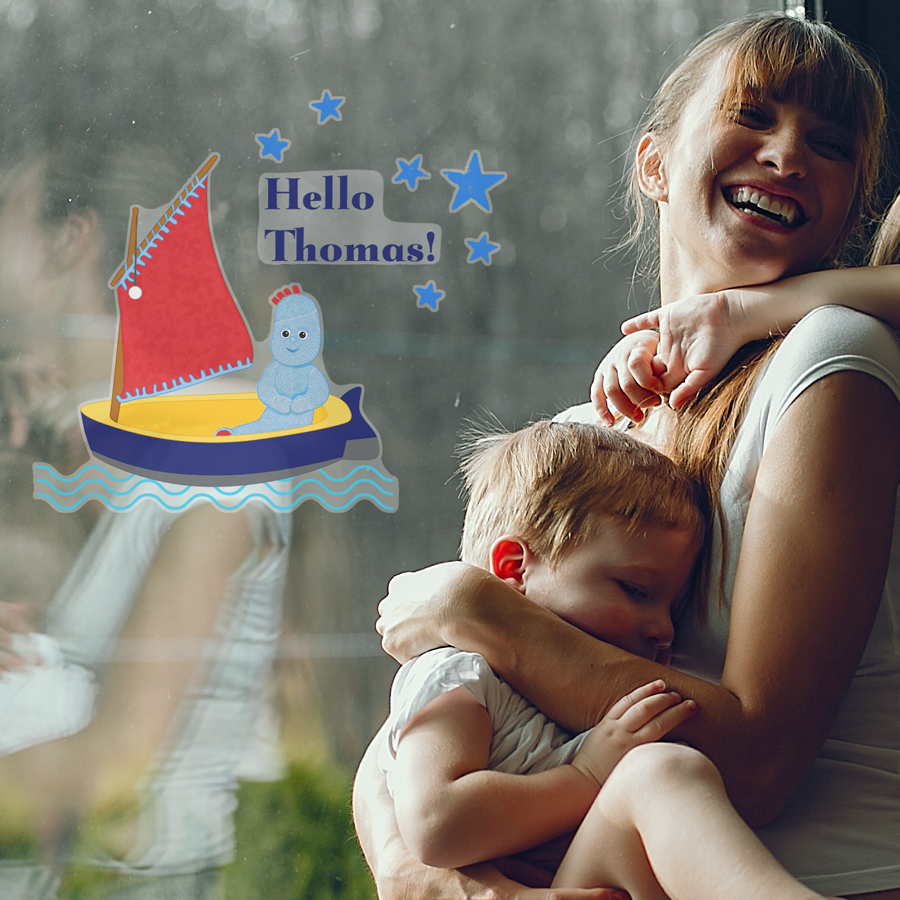 Personalised Hello Igglepiggle window sticker shown on a window behind a happy woman holding a child