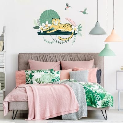 Cheetah and hummingbirds wall sticker pack, jungle wall stickers, safari wall stickers. Featuring a cheetah relaxing on a branch with flowers and green plants around. There is also to pink and green coloured humming birds. Jungle wall sticker, is displayed above a pink bed setting.