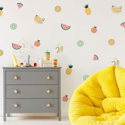 Tropical Fruit wall stickers, jungle wall stickers. Image features tropical fruit stickers on wall around a yellow beanbag chair and a grey set of drawers.
