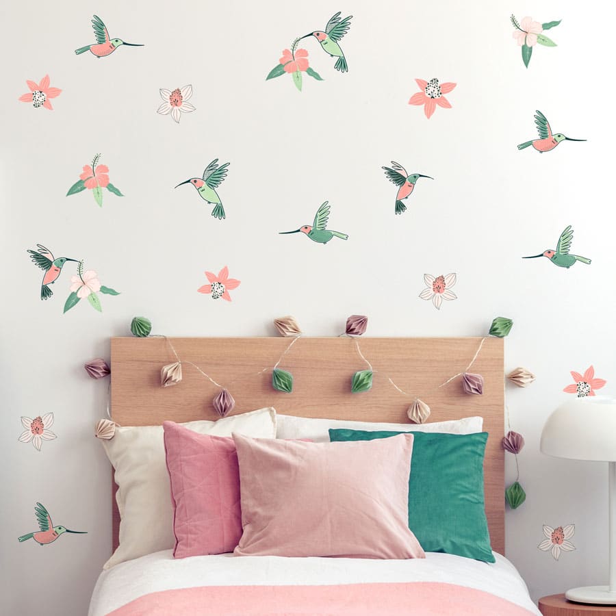 Hummingbird and Hibiscus jungle wall sticker pack. Image shows teal, green and pink hummingbirds and hibiscus flowers on wall around a single bedframe with pink and white bedding.