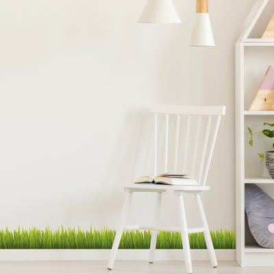 Jungle Grass Wall Sticker shown full length on a light cream wall behind a white chair and bookcase