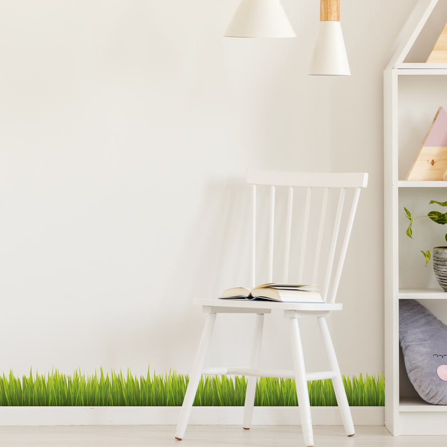 Jungle Grass Wall Sticker shown full length on a light cream wall behind a white chair and bookcase