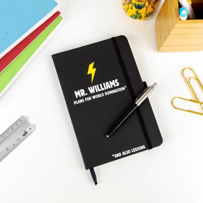 Personalised world domination notebook in black features a yellow lightning bolt with a name of your choice and text 'plans for world domination' all in white and is a perfect gift for a teacher or teaching assistant to say thank you