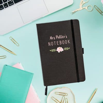 Personalised flower notebook in black features a flower with the text 'notebook' above plus a personalised name and is a perfect gift for a teacher or teaching assistant to say thank you