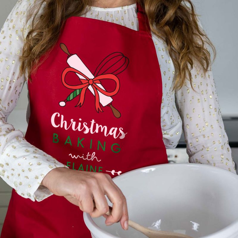 Christmas Baking with apron in red featuring whisk and rolling pin
