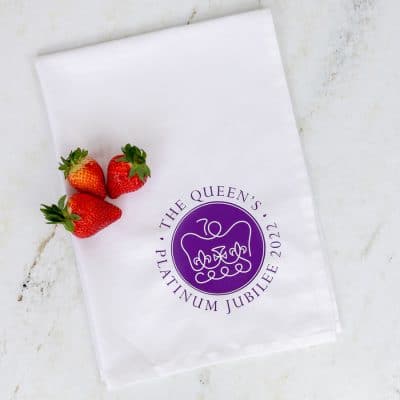 Official platinum jubilee logo tea towel shown flat with strawberries