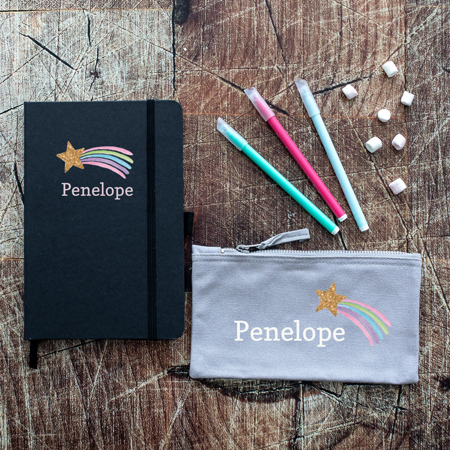 Mini shooting star back to school bundle. Featuring a grey pencil case and a blue notebook with the name penelope in white with a pastel coloured shooting star with a gold glitter effect.