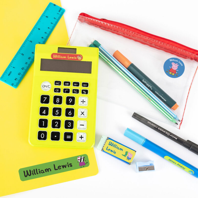 Peppa pig stick on name labels shown stuck to a calculator, pencil case, folder and stationery