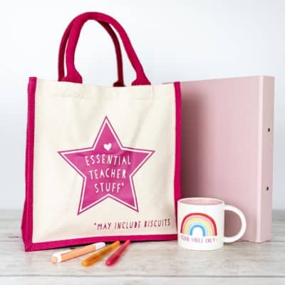 essential teacher canvas bag teacher gift next to folder and teacher's mug and pens