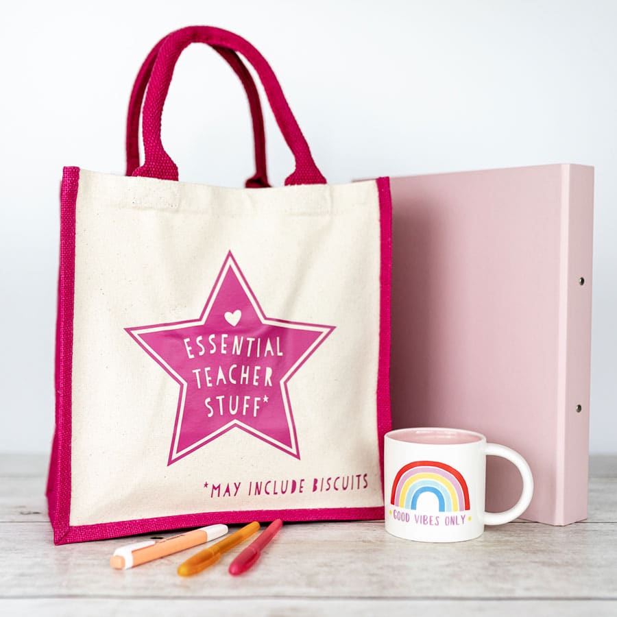 essential teacher canvas bag teacher gift next to folder and teacher's mug and pens