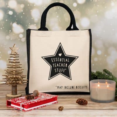 essential teacher canvas bag in black for teachers books on a christmas background with candle