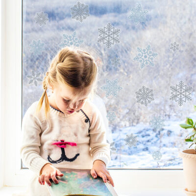 Grey and Blue Snowflake Window Stickers on window behind child
