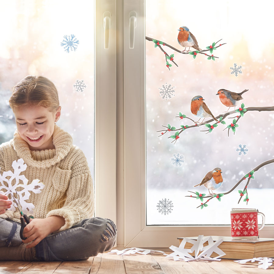 Christmas Robin Window Stickers on a window behind a child making snowflakes