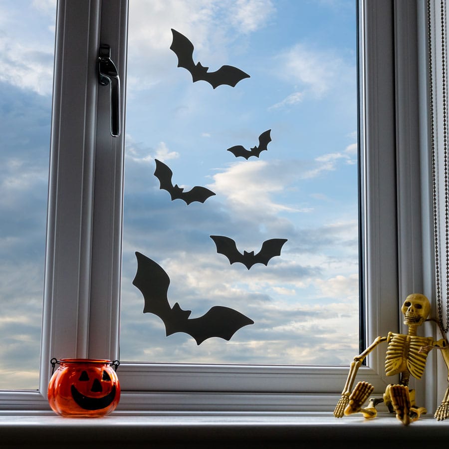 Bat window stickers on a window with skeleton and pumpkin candle holder