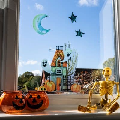 Haunted House Window Sticker with pumpkin and a skeleton on a sunny day