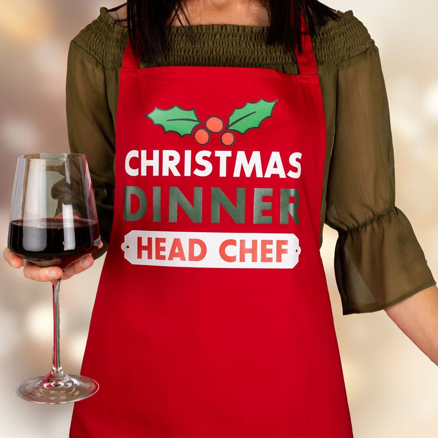 Personalised Christmas dinner apron in red featuring the text head chef on apron on women with wine glass