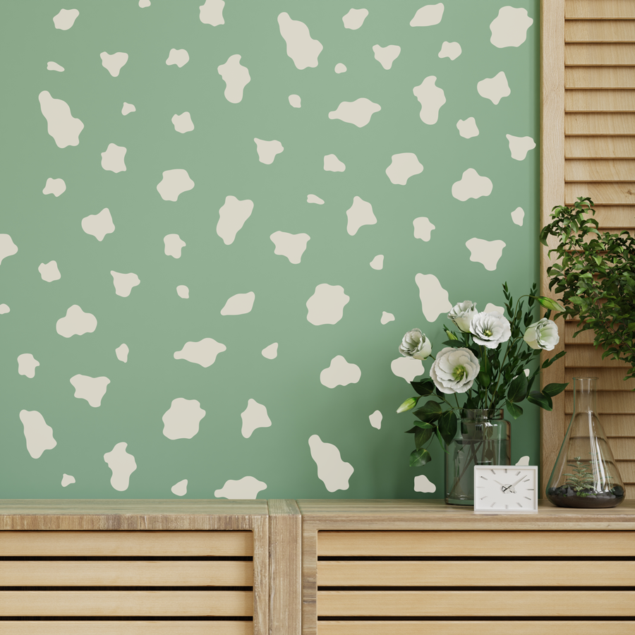 cow print wall sticker pack in light beige shown on a green wall behind a light wooden cabinet