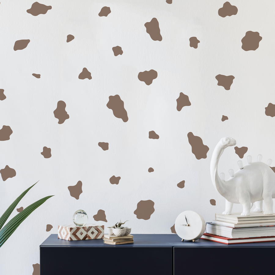 cow print wall sticker pack in brown shown on a white wall behind a navy cabinet