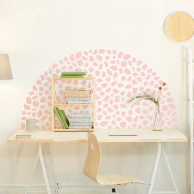 Dalmatian print wall sticker pack in pink shown on a warm white wall in a half circle shape behind a light wooden desk and chair
