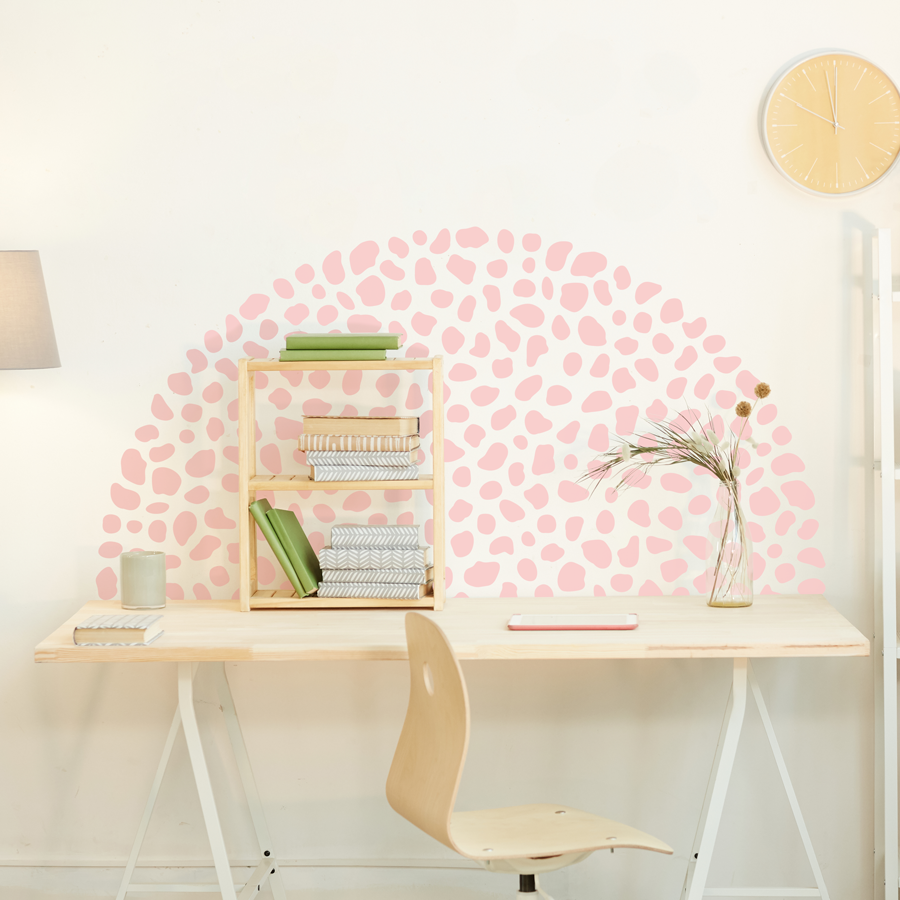 Dalmatian print wall sticker pack in pink shown on a warm white wall in a half circle shape behind a light wooden desk and chair