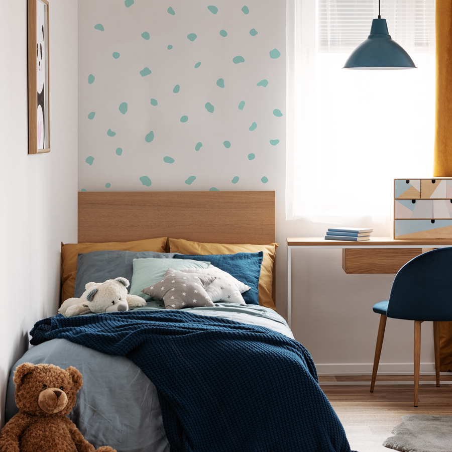 Dalmatian print wall sticker pack in blue shown on a white wall behind a wooden bed with blue sheets