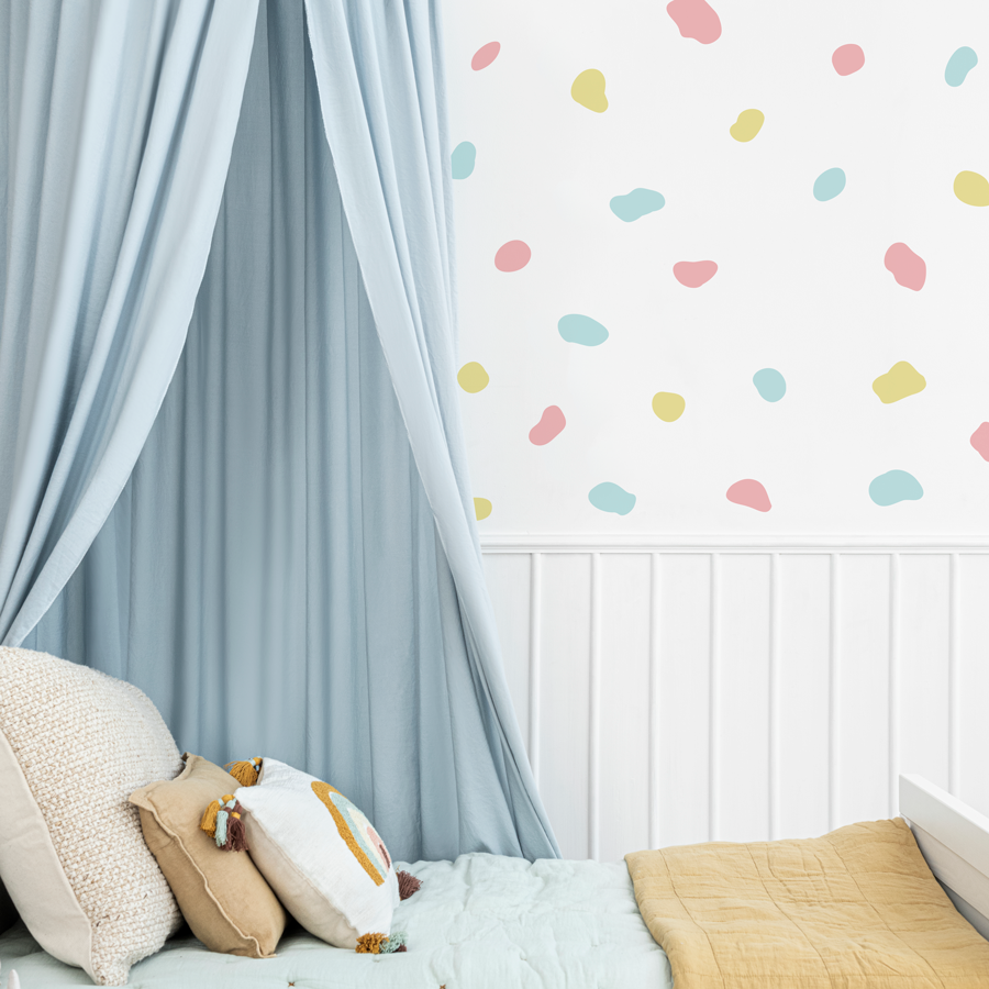 Dalmatian print wall sticker pack in mixed pastels shown on a white wall behind a white bed with a blue canopy
