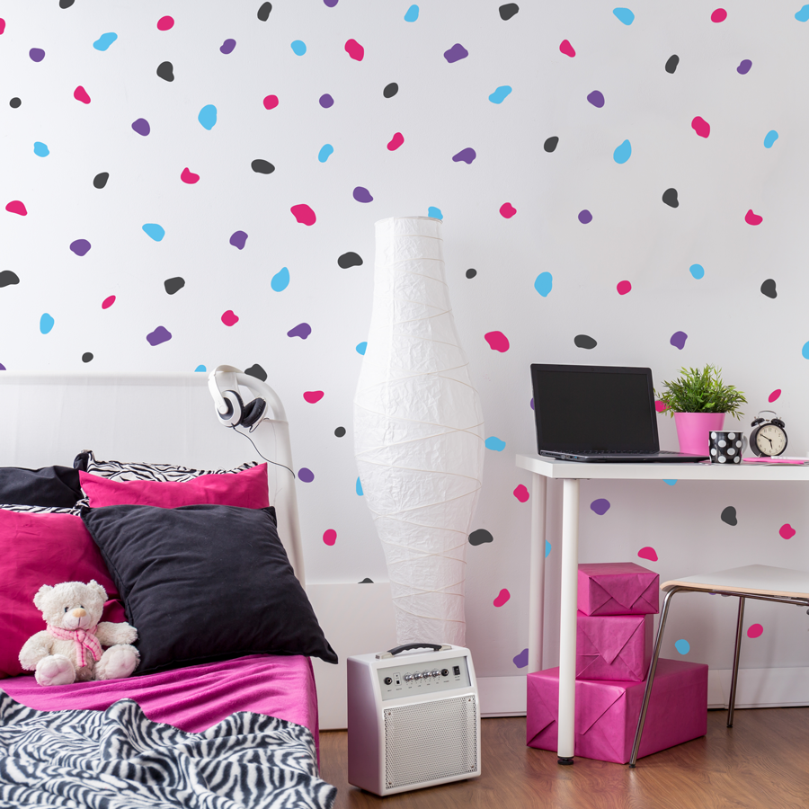 Dalmatian print wall sticker pack in mixed brights shown on a white wall behind a white bed and desk, pink and black bed sheets