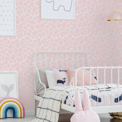 giraffe print wall sticker tile in pink shown on a white wall behind a white bed with light pink bedsheets