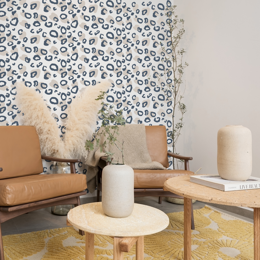 Two tone leopard print wall sticker tile in navy and mushroom shown on a white wall behind brown leather chairs and light coloured pampas