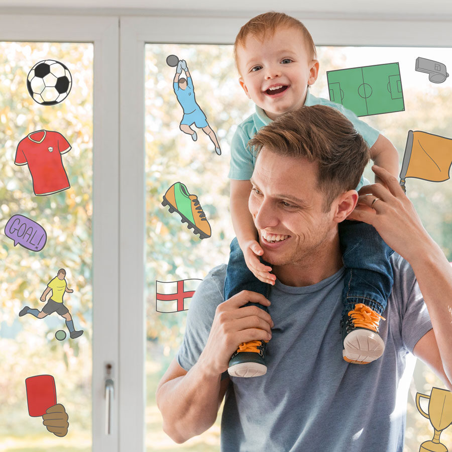 colour-in football window stickers shown coloured in on a window behind a man with a child on his shoulders