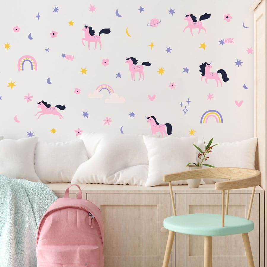 purple & pink unicorn wall sticker pack in regular shown on a white wall in front of a wooden bench with pastel pillows