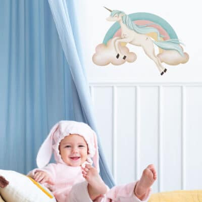 pastel rainbow unicorn wall sticker shown on a white wall behind a blue curtain