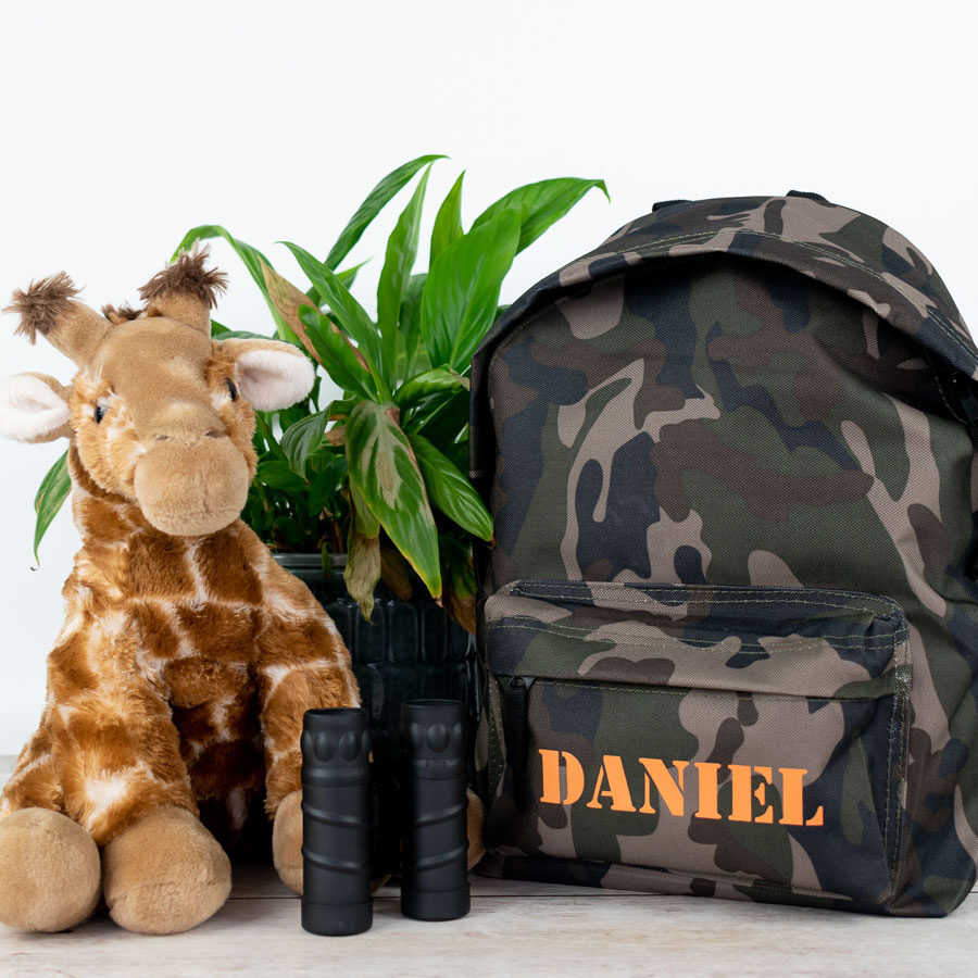 camo stencil backpack bag shown with a stuffed giraffe and binoculars