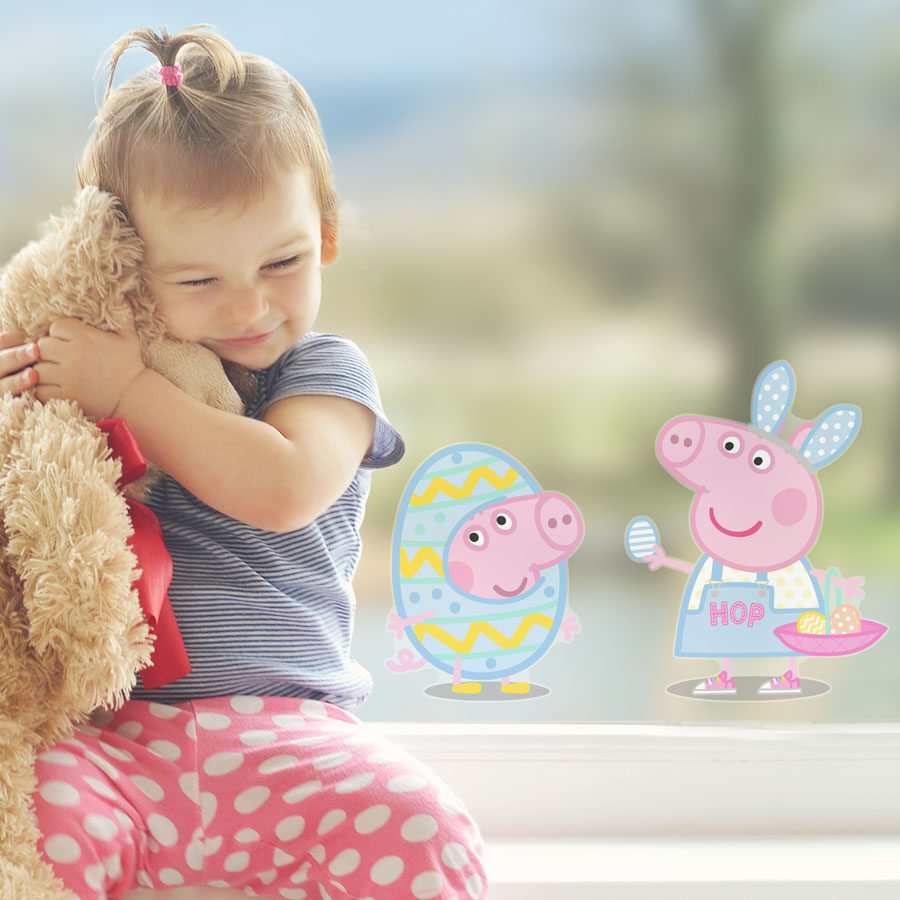 peppa & george easter window sticker shown on a window behind a young girl holding a teddy bear