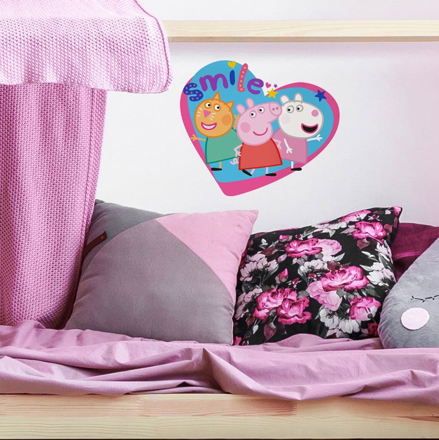 peppa and friends smile wall sticker shown on a white wall behind a pink and grey bed set