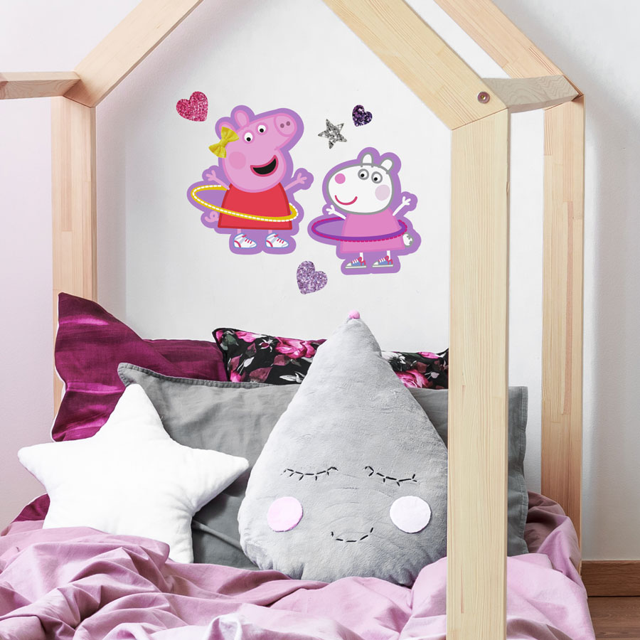 peppa & suzy wall sticker pack regular shown on a white wall behind a bed with pink and grey pillows