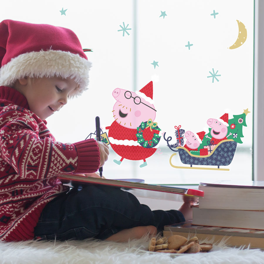 peppa christmas sleigh window sticker shown on a window behing a small child with a christmas hat