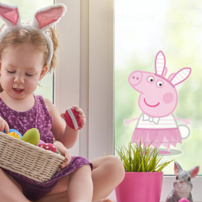 peppa pig easter window sticker shown on a window behind a small girl wearing a rabbit ear headband and holding a basket of colourful easter eggs