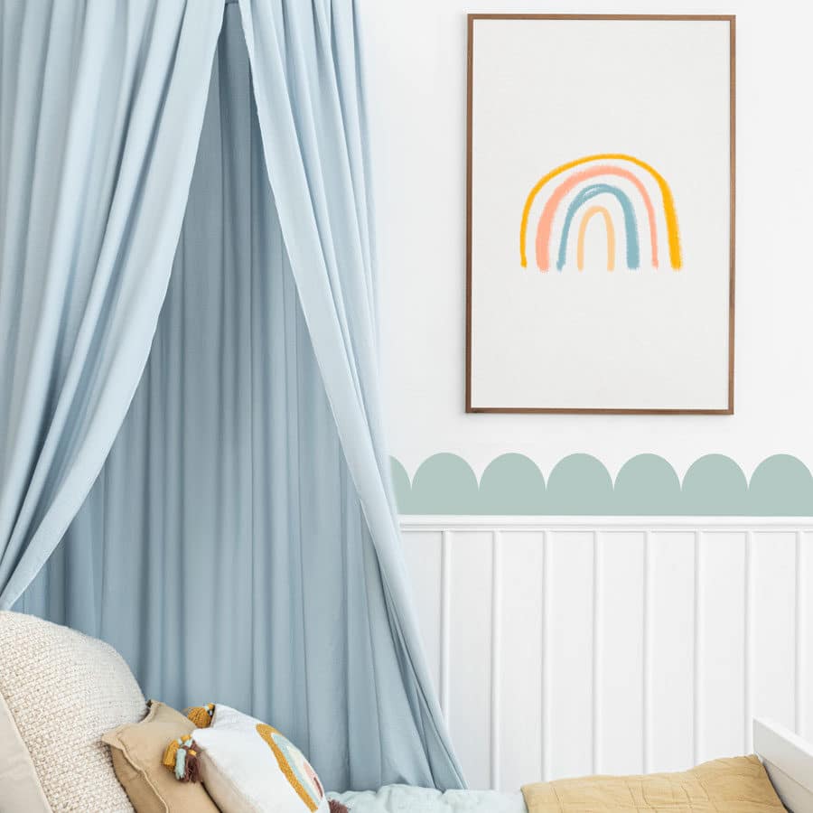 scallop wall stickers in light blue on a wall above some panelling behind a light blue bed and under a print of a rainbow