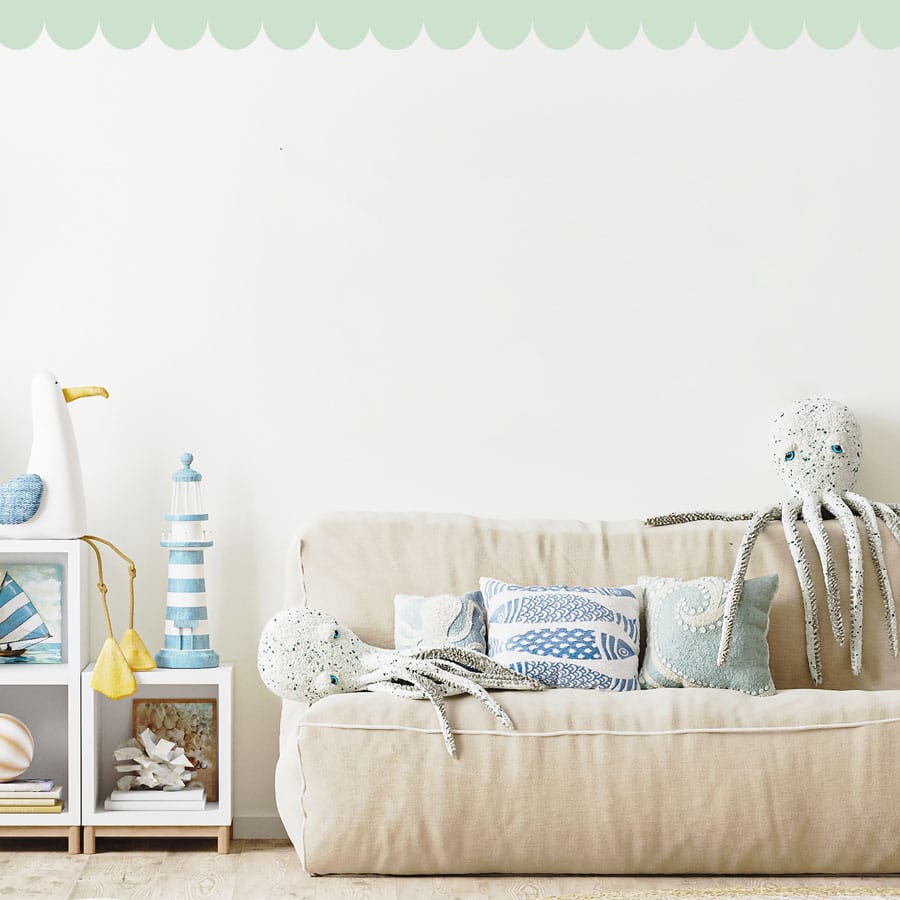 scallop wall stickers in mint on a white wall behind a light cream sofa in a nursery