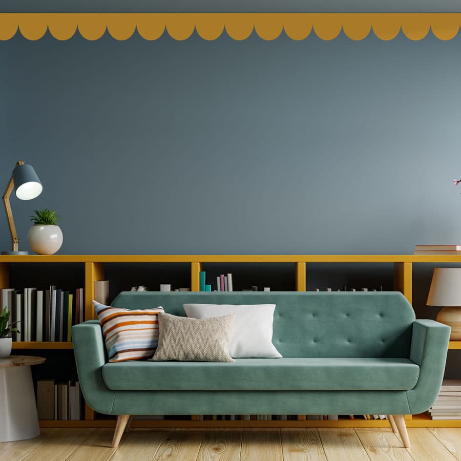 scallop wall stickers in mustard shown on a grey blue wall above a teal sofa and matching bookcase