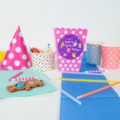Peppa pig party bag label pack in purple on a pink spotty party bag next to other party accessories