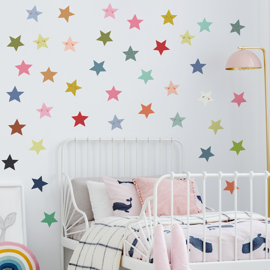 smiley stars wall sticker pack large shown on a light grey wall behind a small white bedframe with pink, blue and white bedspread