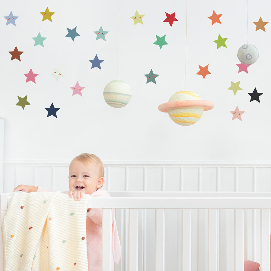 smiley stars wall sticker pack shown on a white wall above a white cot with a baby in it