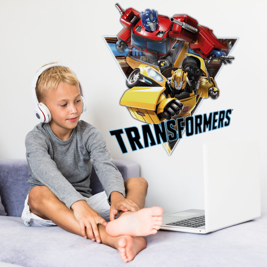Transformers triangle wall sticker large shown on a wall behind a boy using a laptop