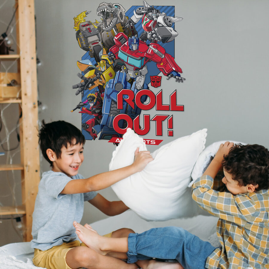 Transformers roll out wall sticker large shown on a grey wall behind two boys having a pillow fight