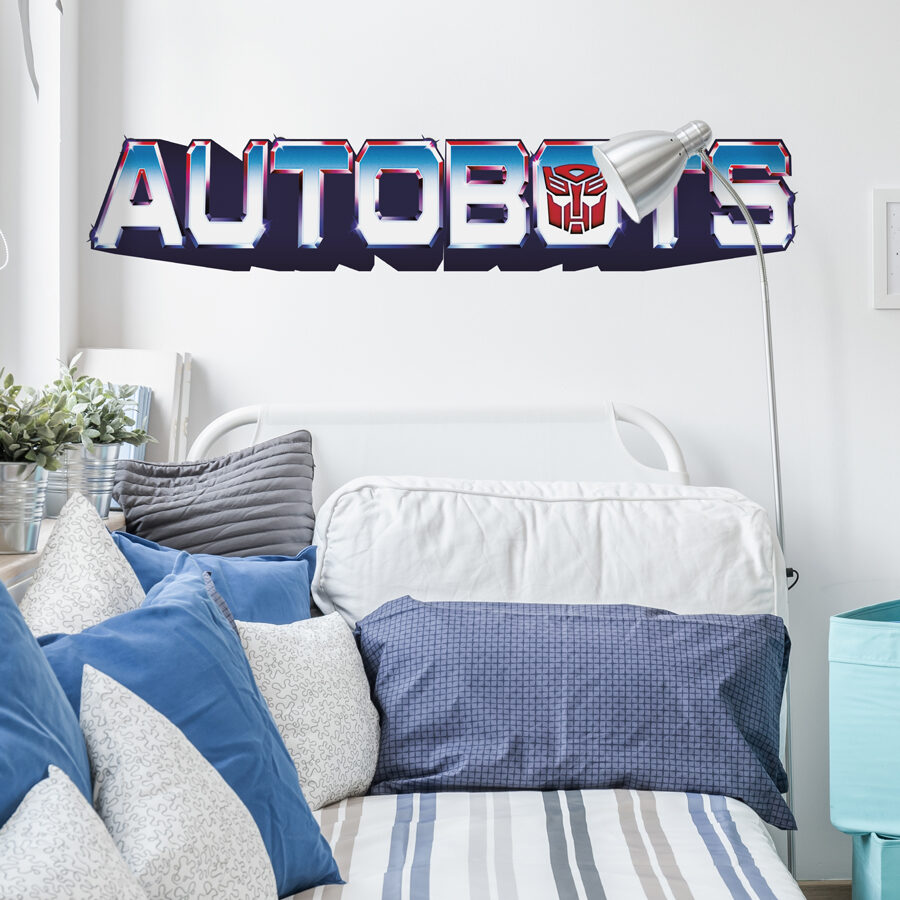 Autobots wall sticker large shown on a white wall behind a white and blue bed