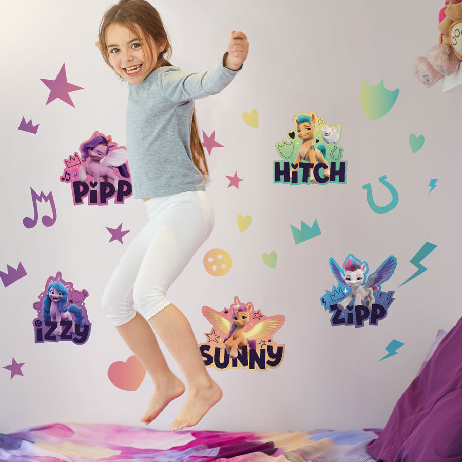 My Little Pony wall sticker pack shown on a white wall behind a purple bed with a child jumping on it